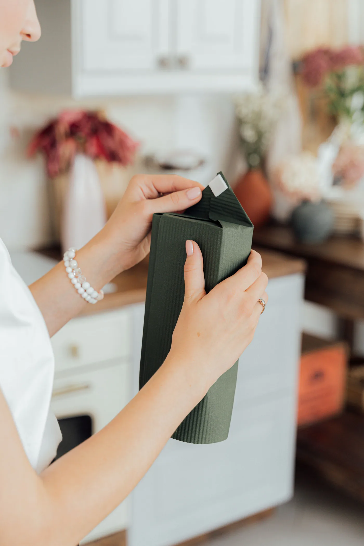 Hands carefully finishing a deep green gift box